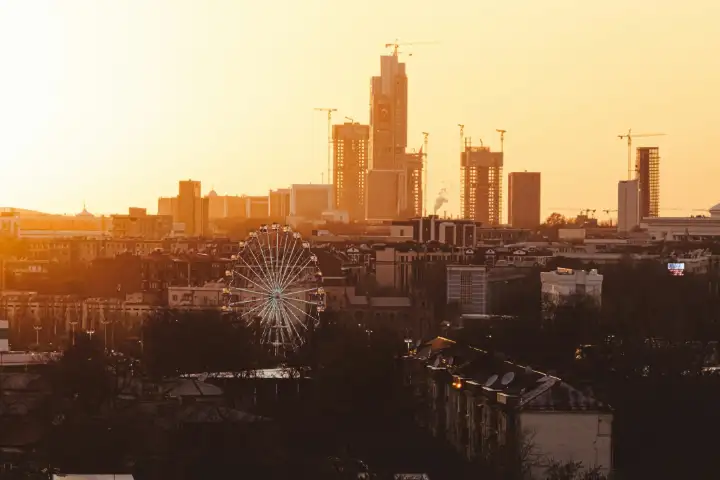 The Tashkent skyline at sunset, with high-rise towers and a Ferris wheel